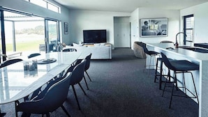 A modern kitchen with a dining area, a large TV, and a bar.