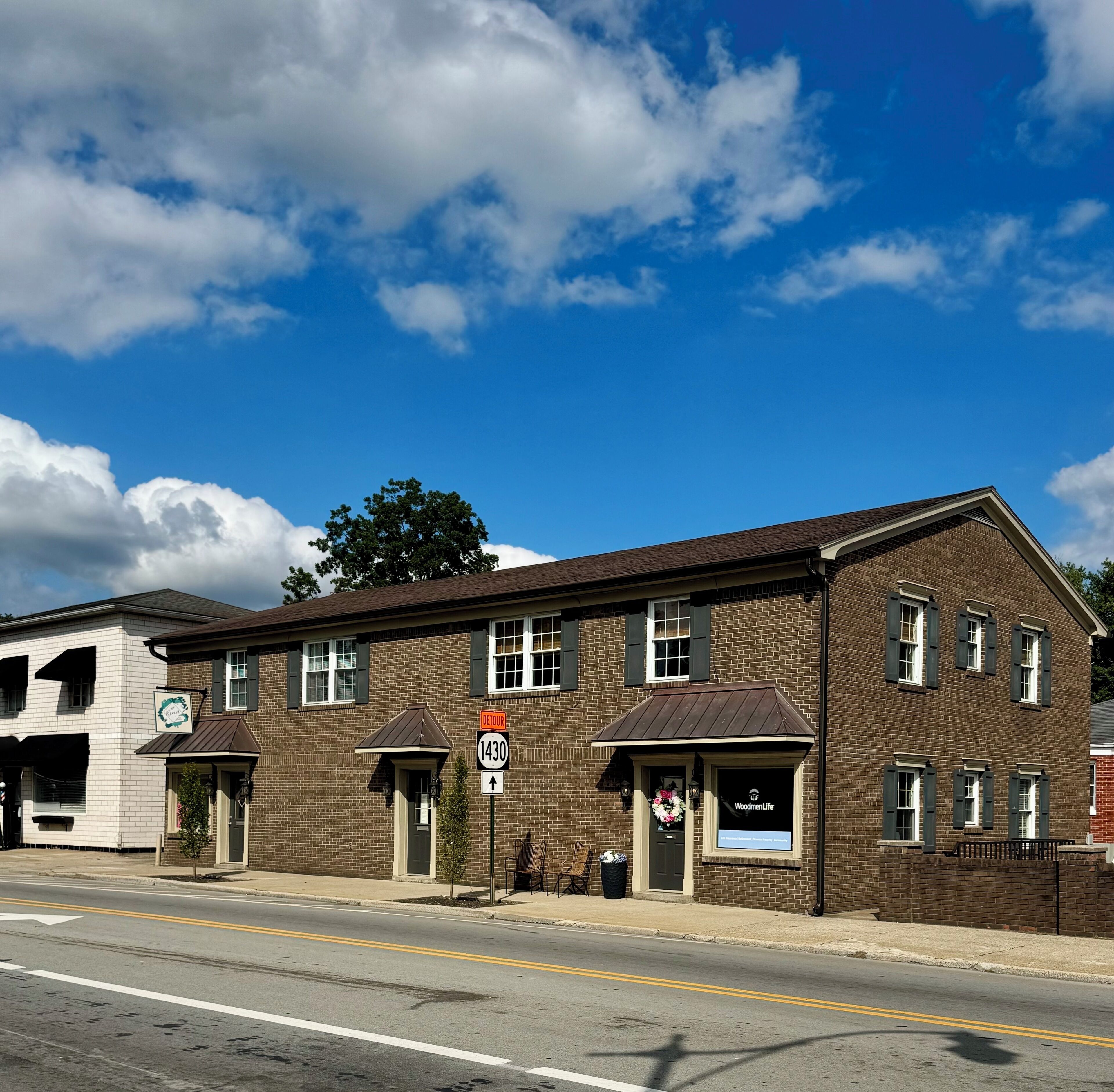 A two-story brick building with a sign for 'Woodmen Life' and a 'Detour' sign indicating a route change.
