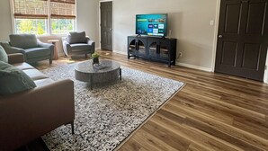 Ein Wohnzimmer mit einem großen Fernseher, zwei Sofas, einem Couchtisch und einem gemusterten Teppich.