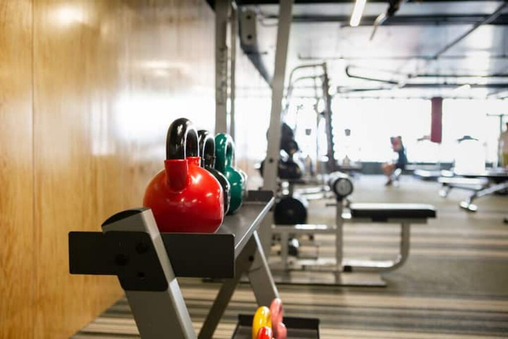 Kuntosali, jossa on telineessä kettlebell-painoja ja taustalla näkyy muita kuntoiluvälineitä.