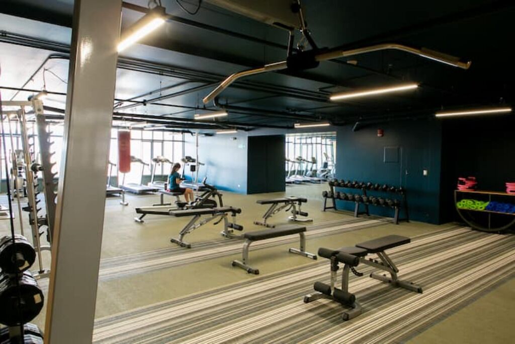A gym with exercise equipment, a bench, and dumbbells.