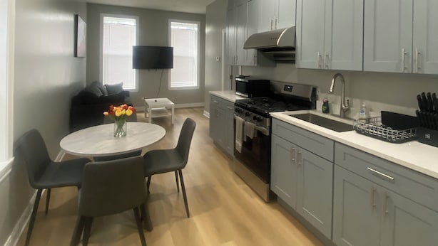A modern kitchen with grey cabinets, a stainless steel stove, and a white countertop.