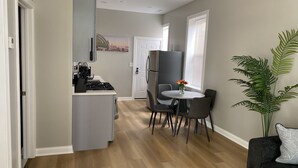 A modern kitchen with a built-in stove, a refrigerator, and a dining area with a table and chairs.