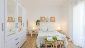 Un dormitorio con cama, mesitas de noche, armario y espejo.