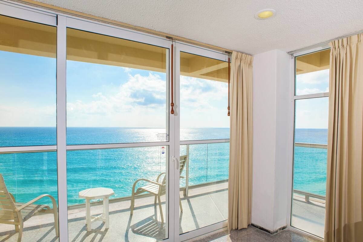Un balcon avec vue sur l’océan, une chaise et une petite table.