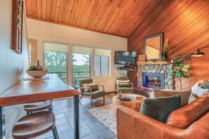 Una sala de estar acogedora con techo de madera, chimenea, televisor y asientos cómodos.