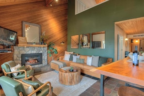 A cozy living room with a stone fireplace, leather seating, a wooden coffee table, and a bar area.