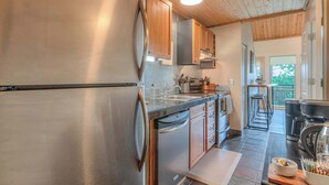 Une cuisine moderne dotée d’appareils électroménagers en acier inoxydable, de meubles en bois et offrant une vue sur l’extérieur.