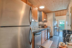 A modern kitchen with stainless steel appliances, wooden cabinets, and a view to the outside.