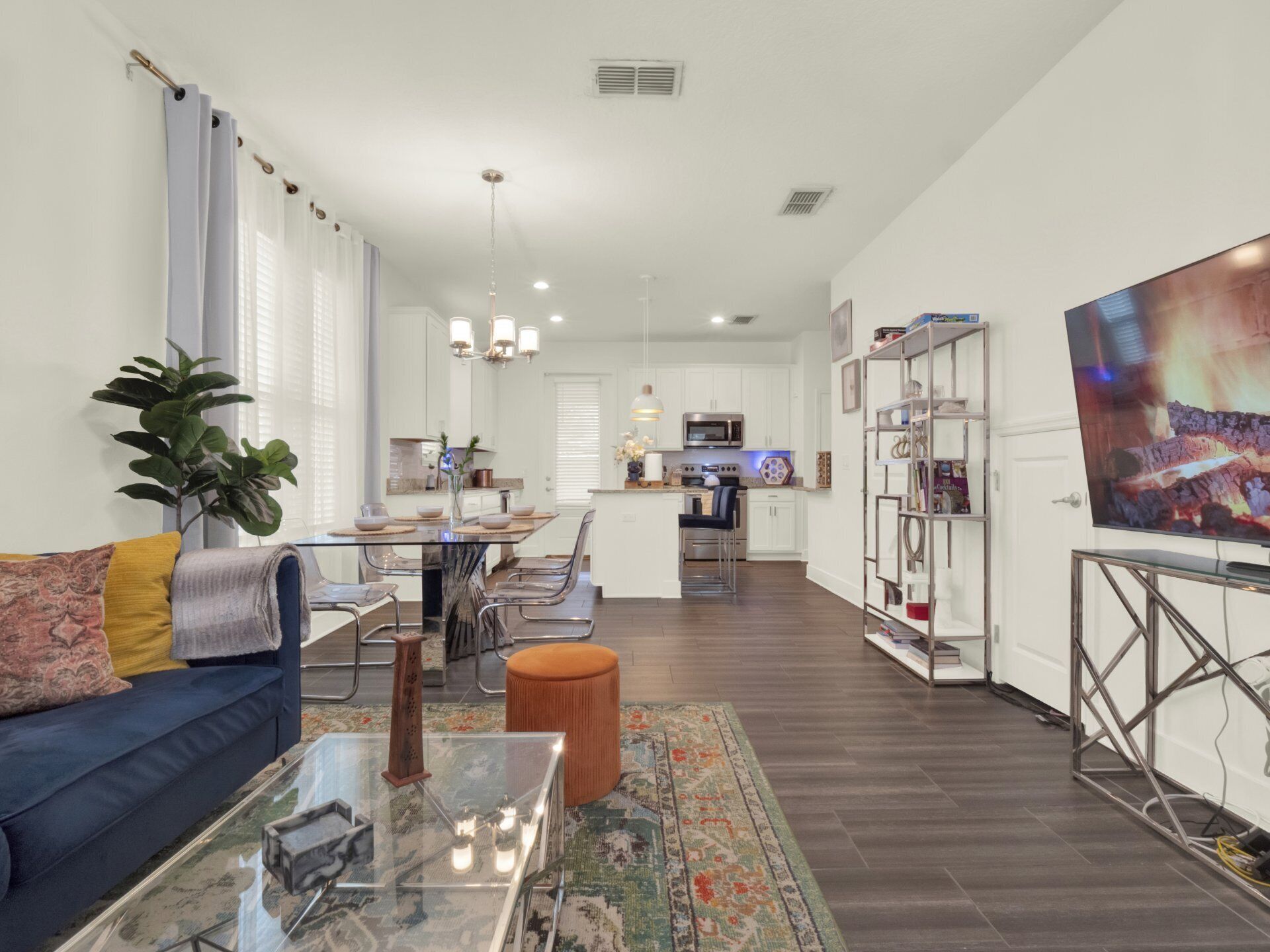 A modern living room with a sofa, coffee table, and a dining area with chairs and a table.