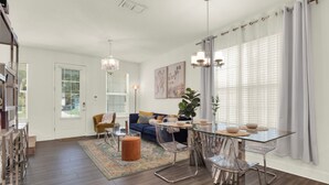 A modern living room with a glass dining table, clear chairs, a sofa, and a coffee table.