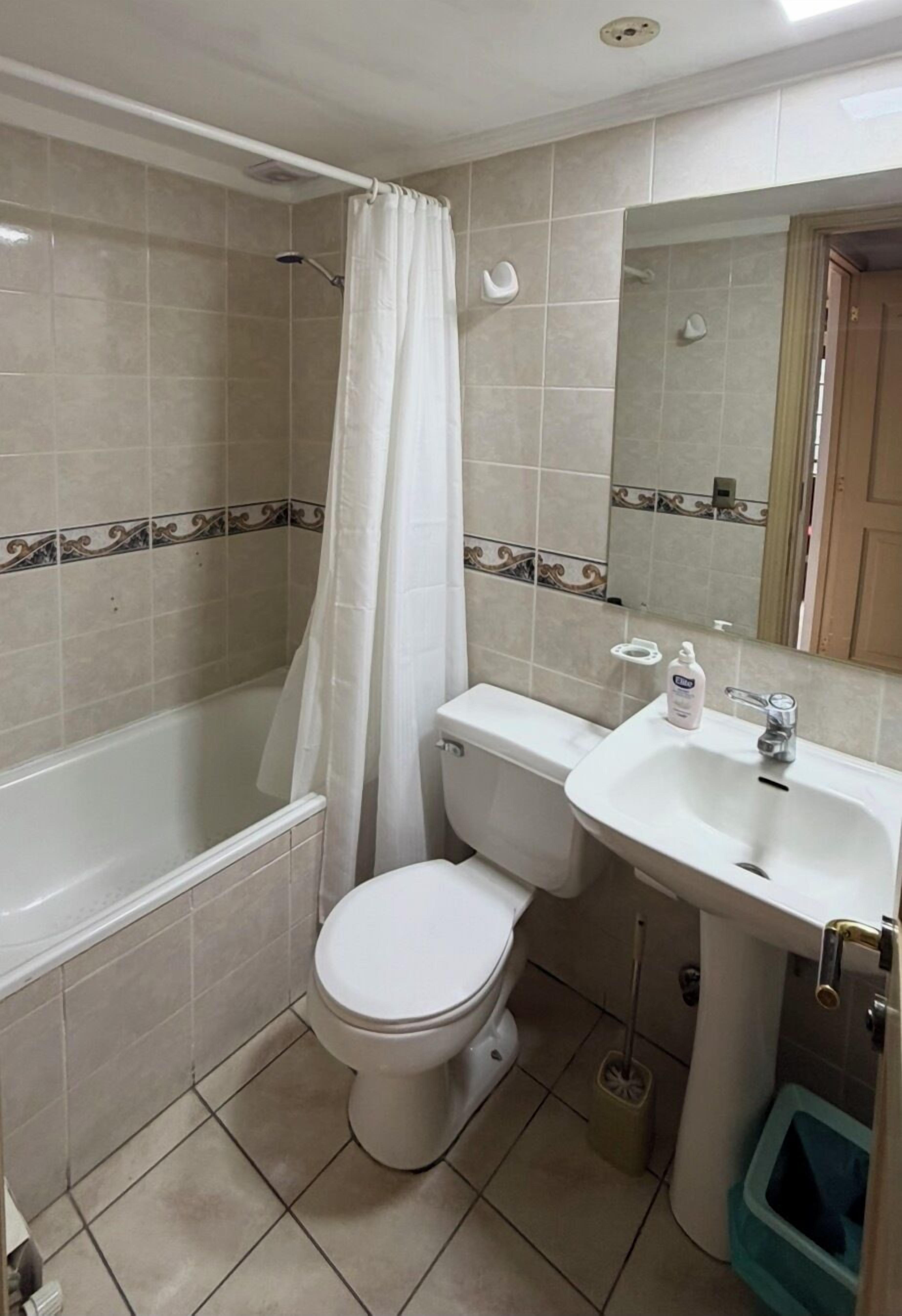 A bathroom with a bathtub, toilet, sink, and a mirror.