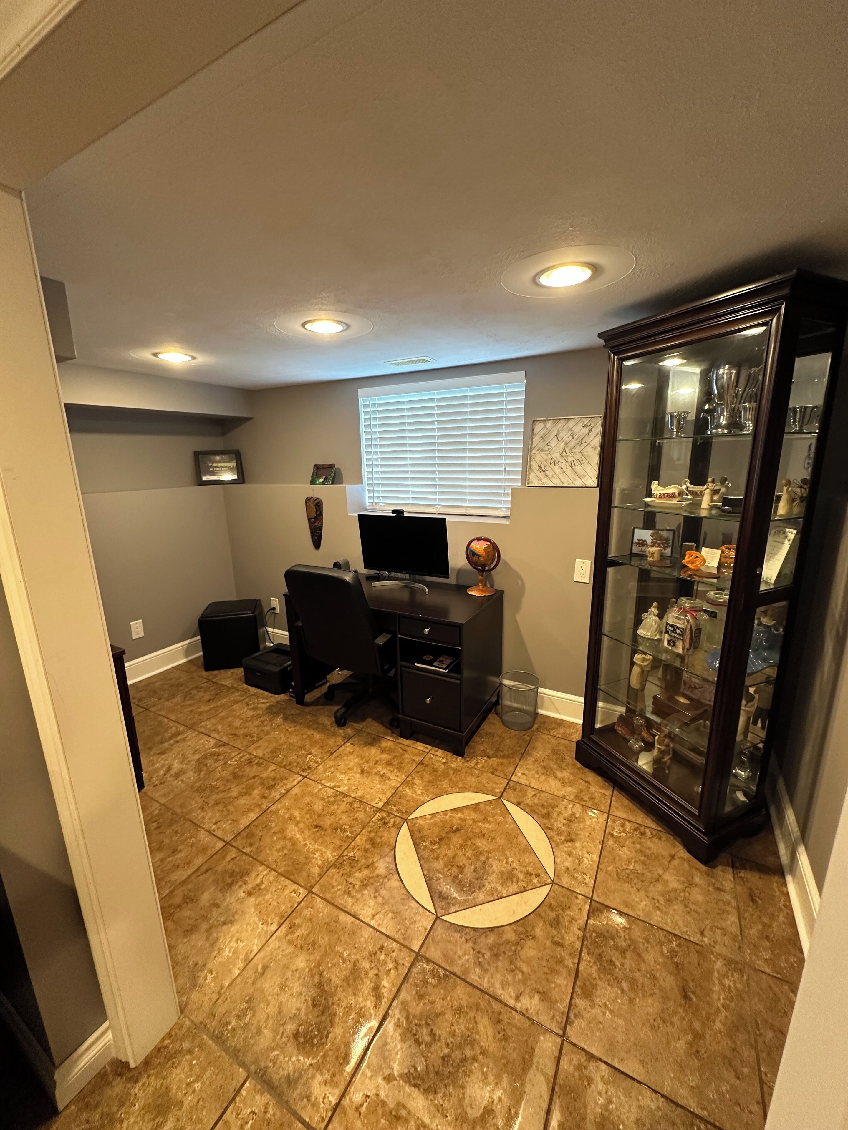 A home office with a desk, computer, and a glass display cabinet.