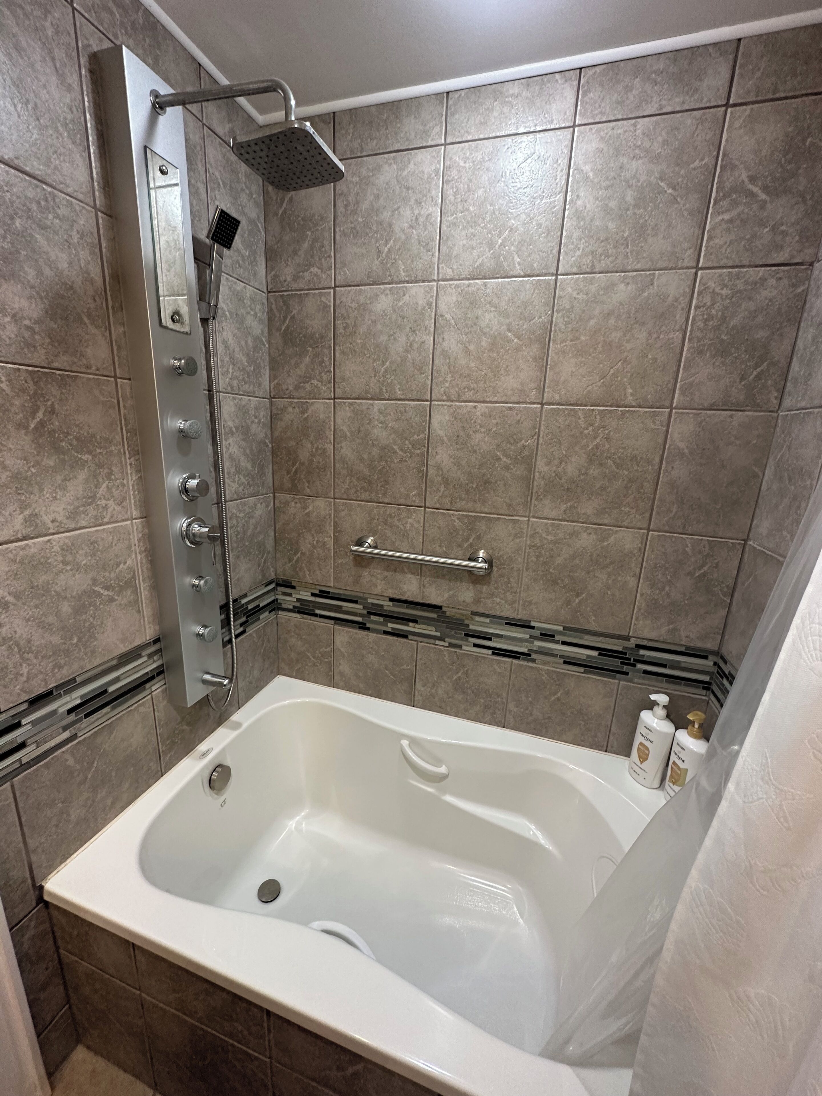 Une salle de bain moderne avec une douche à l’italienne, une baignoire et un sol carrelé.