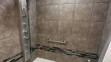 Une salle de bain moderne avec une douche à l’italienne, une baignoire et un sol carrelé.