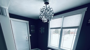 Ein Zimmer mit einer Bank, einer Tür, einem Fenster und einer Kristallleuchter.