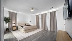 Un dormitorio moderno con una cama, una mesita de noche, un televisor y un banco de madera.