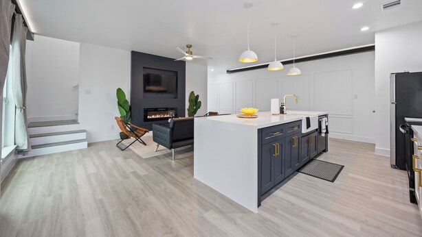 A modern kitchen with a central island, white cabinetry, and a built-in stove.