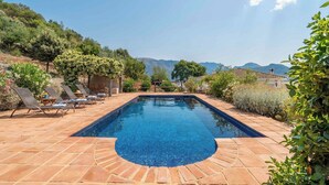 A rectangular swimming pool with a tiled edge, surrounded by a patio with lounge chairs and a stone floor. - Cozy Paradise El Gastor by Ruralidays (Cádiz)