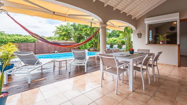 A covered outdoor area with a pool, lounge chairs, and a dining table. - Villa Blue Cane with a pool and ping-pong table, perfect for families (Le MOULE)