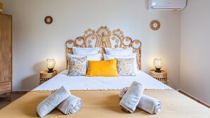 A neatly made bed with white and yellow bedding, two bedside lamps, and a large air conditioning unit on the wall. - Villa Blue Cane with a pool and ping-pong table, perfect for families (Le MOULE)