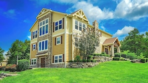 A multi-story house with a stone facade, large windows, and a well-maintained lawn. - Branson Retreat Lodge – Hot Tub, Pools & Game Room (Hollister)