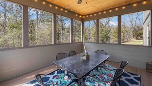 Une terrasse couverte avec une table et des chaises, de grandes fenĂŞtres et un ventilateur de plafond.