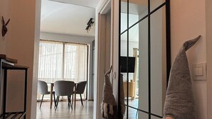 Een moderne woonkamer met een eethoek, een grote spiegel en decoratieve dwergbeeldjes.