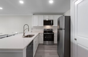 Una cocina moderna con armarios blancos, electrodomésticos de acero inoxidable y una isla central.