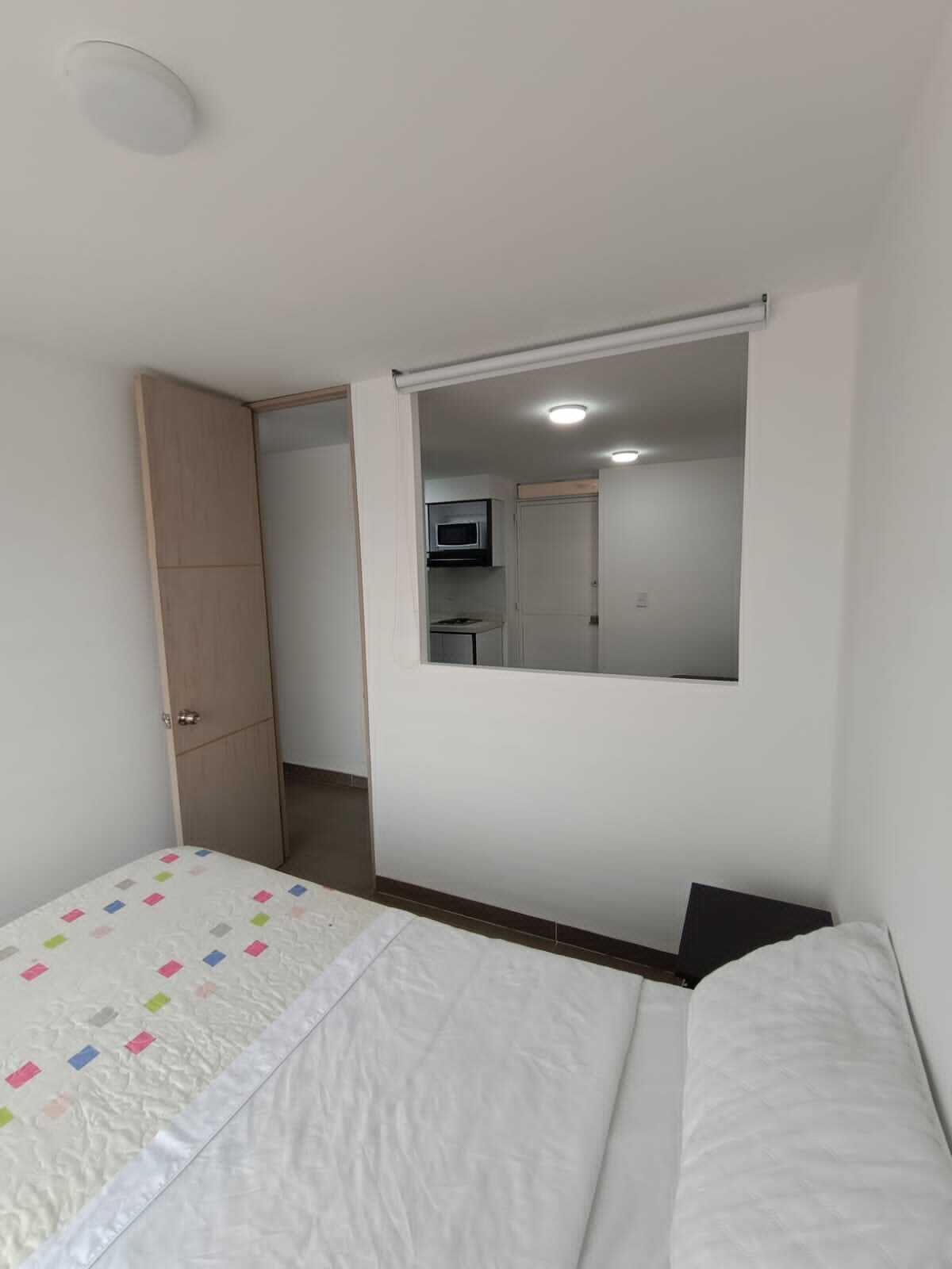 Un dormitorio con cama, armario, espejo y puerta que da a un baño.