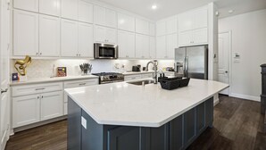 Una cocina moderna con armarios blancos, electrodomésticos de acero inoxidable y una isla grande.