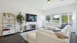 Una sala de estar moderna con un sofá blanco, una mesa de centro, un televisor y una estantería.