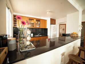 Une cuisine moderne avec des meubles en bois, un plan de travail noir et un îlot central agrémenté d’un vase de fleurs.