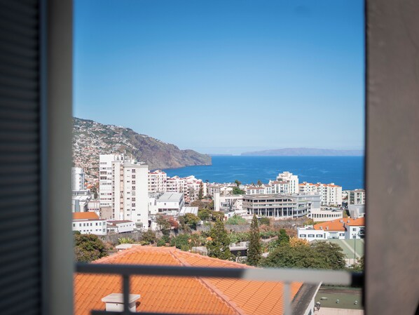 A coastal cityscape with buildings, a clear sky, and the sea in the background.