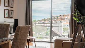 Un salon moderne doté d’une grande porte-fenêtre coulissante donnant sur un balcon avec vue sur la ville.