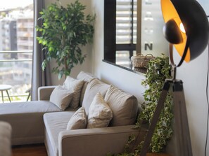 A modern living room with a sofa, a potted plant, and a floor lamp.