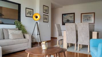 Un salon moderne comprenant un canapé, une table à manger avec des chaises, une lampe sur pied et des œuvres d’art encadrées accrochées aux murs.