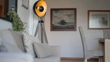 Un salon moderne avec un canapé, une lampe sur pied, un fauteuil et des œuvres d’art encadrées accrochées au mur.