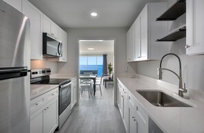 Una cocina moderna con armarios blancos, electrodomésticos de acero inoxidable y vistas al exterior.