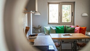 Een gezellig eetgedeelte met een houten tafel, een schaal noten en een gestreepte vaas.