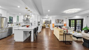 A modern kitchen with white cabinetry, a central island, and a dining area. - Lux•PrimeLocation•HtdResortPool•OutdrDining (West Palm Beach)