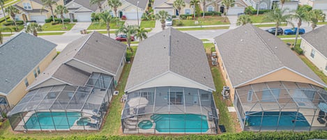 A residential area with multiple houses, each featuring a swimming pool with a glass enclosure.