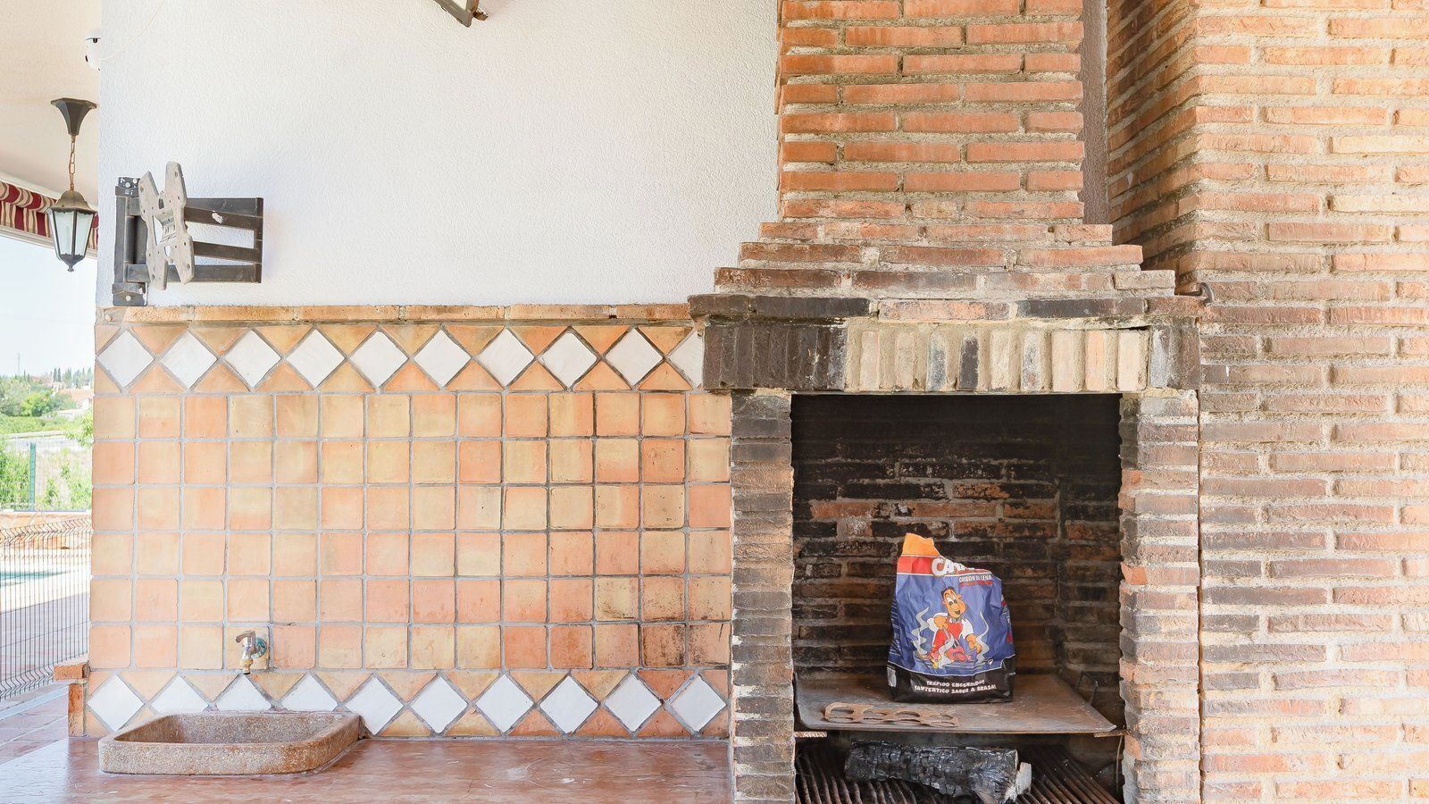 Una chimenea de ladrillo con un revoque de azulejos y un saco de carbón sobre el hogar.