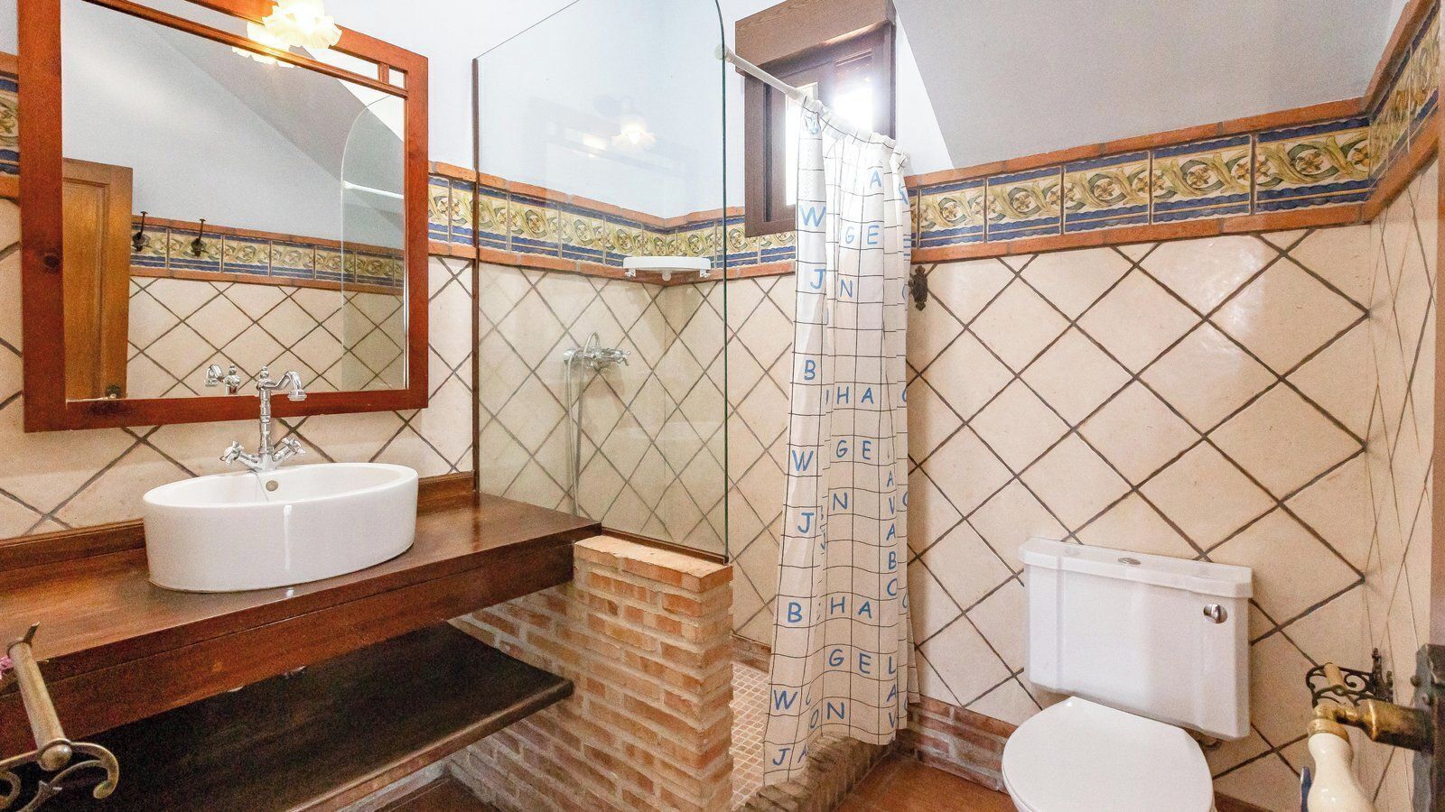 A bathroom with a sink, mirror, shower, and toilet.