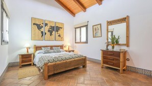 A bedroom with a bed, bedside tables, a dresser, a mirror, and a world map on the wall. - Finca Mis Morenas Moguer by Ruralidays (Huelva)