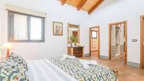 A bedroom with a bed, a dresser, a mirror, and a window.