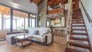 A spacious living area with a large sofa, a coffee table, and a staircase. - Finca Mis Morenas Moguer by Ruralidays (Huelva)