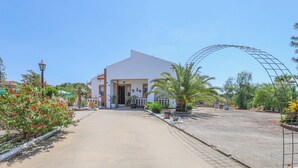 A building with a white facade, a curved entrance, and a paved driveway.