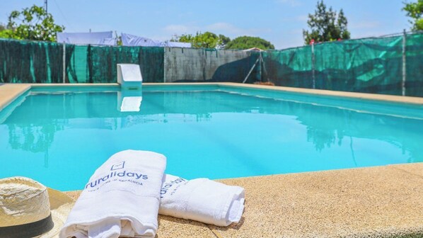 Una piscina cristalina con una toalla blanca y un sombrero en el borde.