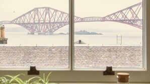 A window with a view of a bridge and a brick wall.